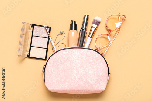 Bag with cosmetics and accessories on beige background
