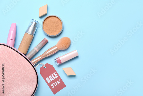 Bag with cosmetics, accessories and sale tag on blue background
