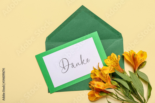 Card with word DANKE, envelope and flowers on beige background