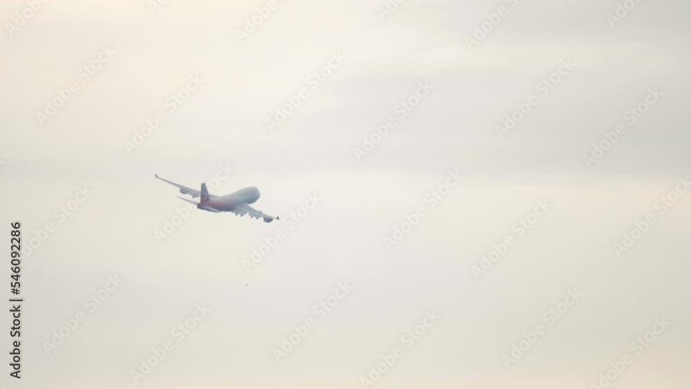 Passenger widebody aircraft flying away. Jumbo jet departure, long shot. Airliner climb after takeoff. Tourism and travel concept