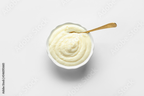 Ramekin of tasty pudding with spoon on grey background