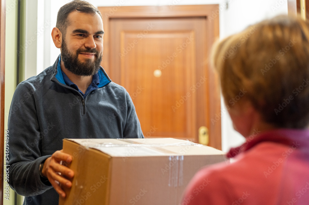 Bearded man delivering a package to a lady. Holding a parcel in front of the door. Bearded man delivering a package to a lady. Holding a parcel in front of the door.
