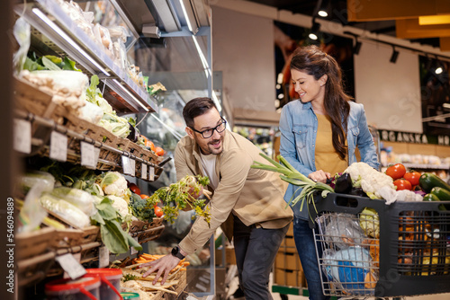 Canvas Print Happy couple is purchasing vegetables in supermarket.