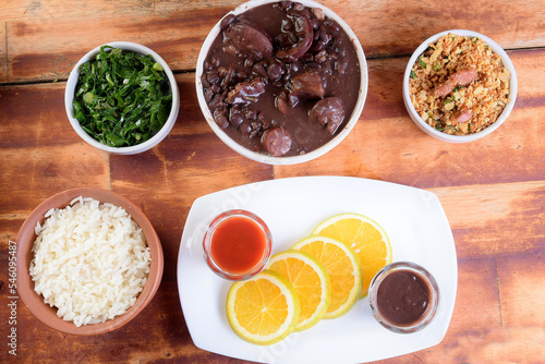 delicious Brazilian feijoada with farofa rice salad served in bowl over piece of wood on blurred background  Brazilian food