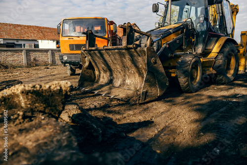 An excavator digging asphalt on country road.
