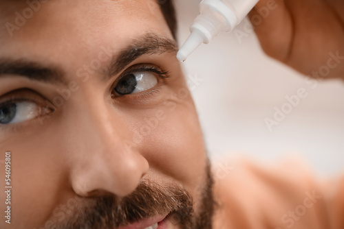 Handsome man using eye drop...
