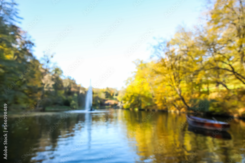 Blurred view of beautiful lake with boat and yellow trees