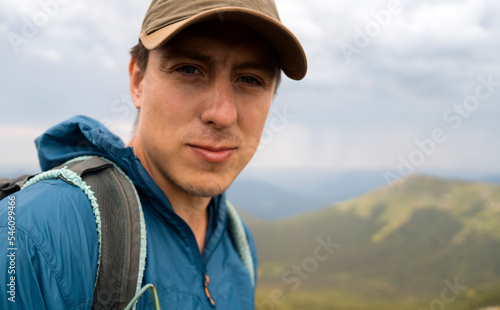 Young traveler is hiking in the mountains, portrait of a man closeup.