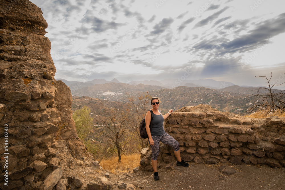 A female tourist at the remains of Bentomiz castle which was a moorish constructed fort on the top of a hill near Arenas in the mountains of Andalusia above Malaga. Spanish name is Castillo Bentomiz