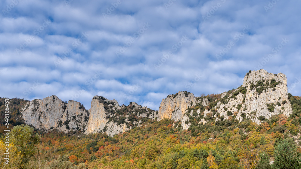 Scenic autumn landscape with rocky cliff and colorful forest in the lower Pyrenees mountains, Salvezines, Aude, France