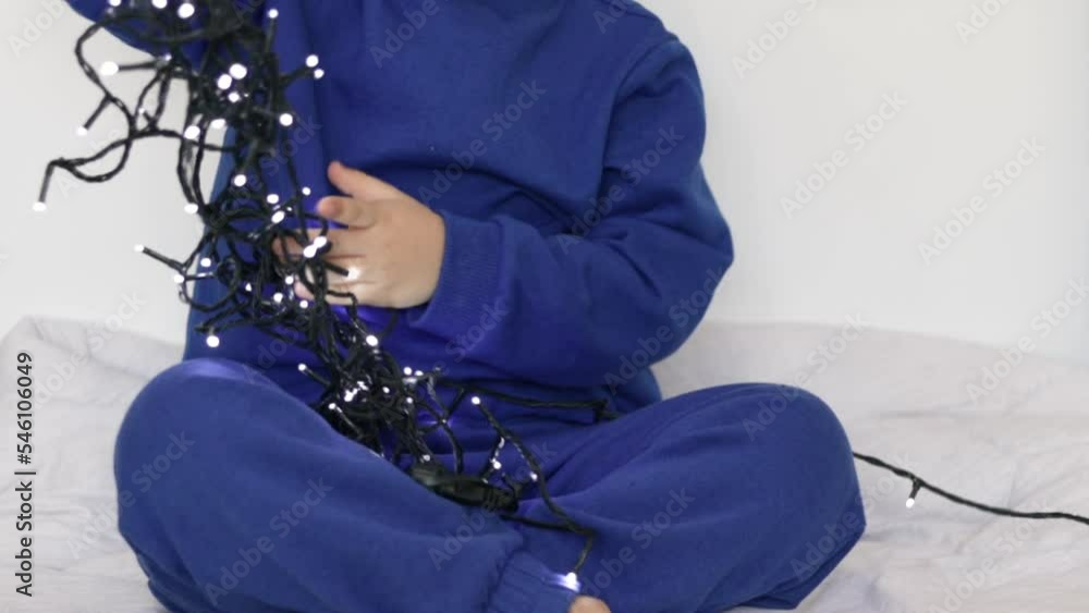 adorable kid preschooler playing with christmas lights inside home bed
