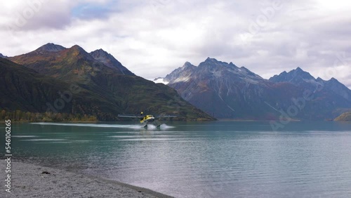 float plane lands on water in alaska in mountain range area near by homer cool avaition plane for travel etc photo