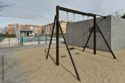 Dark wooden swing structure and a covered swimming pool in winter