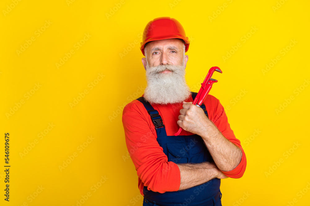 Photo of confident senior carpenter offer fixing service hold pipe fitter isolated on bright color background Photo of confident senior carpenter offer fixing service hold pipe fitter isolated on bright color background