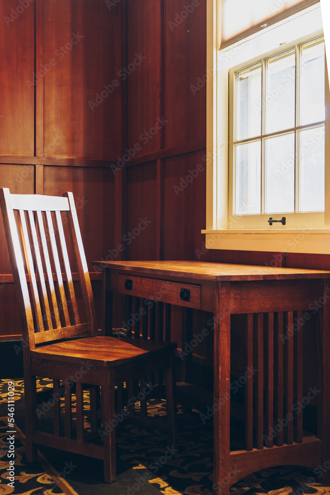Wooden desk and chair by a bright window as sunshine beams in Wooden desk and chair by a bright window as sunshine beams in