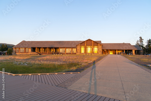 Old Faithful Lodge at Yellowstone National Park at sunset, with the long shadow of a tourist on the boardwalks