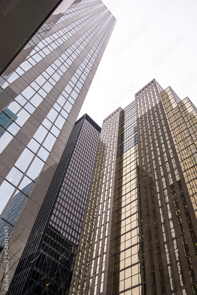 Obraz premium Tall offices buildings against a grey overcast sky in downtown business district.