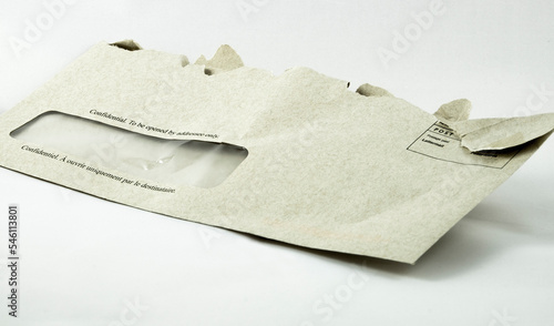 A light grey window envelope that has been torn open with the words 'Confidential. To be opened by addressee only' printed on the front in both English and French. photo