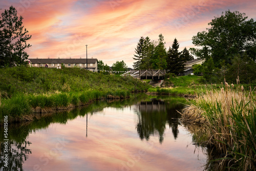 Small creek in a community recreation area with a sunset reflecting on the water at Nose Creek Park Airdrie Alberta Canada.