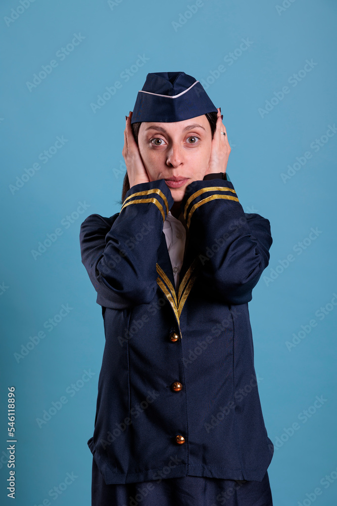 Flight attendant covering ears with hands, showing hear no evil gesture. Airplane stewardess looking at camera front view, no listen sign, three wise monkeys wisdom concept Flight attendant covering ears with hands, showing hear no evil gesture. Airplane stewardess looking at camera front view, no listen sign, three wise monkeys wisdom concept