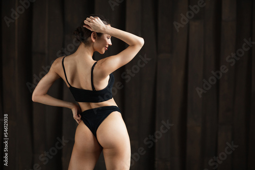 Beautiful sexy woman with fit body in lingerie posing full length back view in studio.