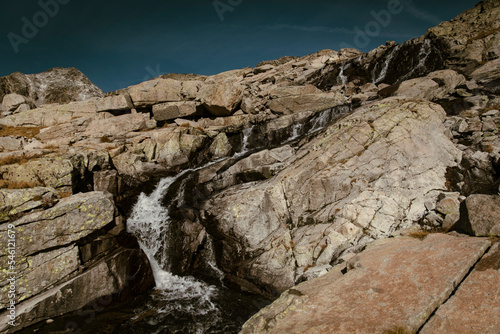 Waterfall running down some mountain rocks during a clear day