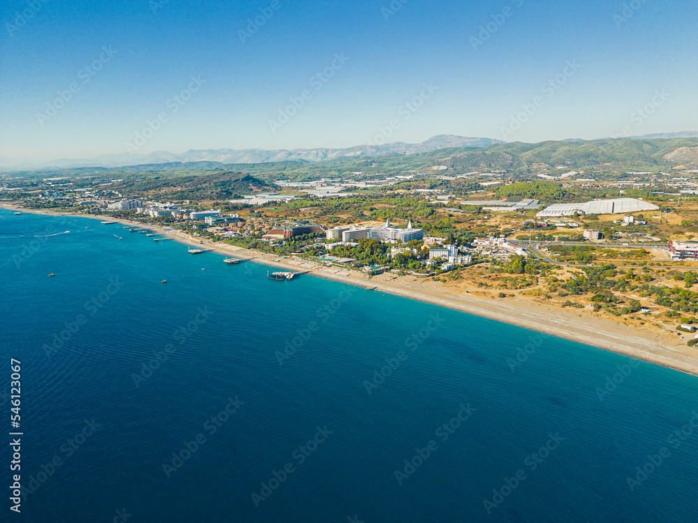 Birdseye panoramic view of seashore with beach and resorts in Ocurcalar, Turkey. Clear blue water and blurred horizon line. Tourist destination. Horizontal shot. High quality photo