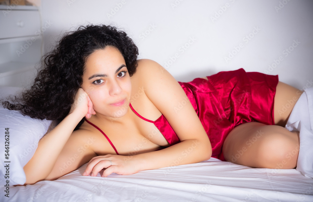 Naklejka premium Portrait of long-haired brunette woman in lingerie enjoying lying in bed