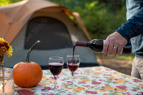 Fototapeta Naklejka Na Ścianę i Meble -  Man pouring wine at a campsite picnic table