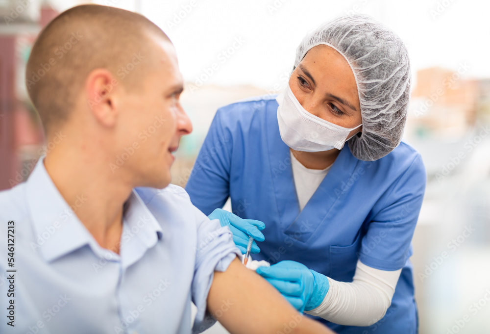 Doctor woman giving coronavirus vaccine to european middle-aged man in vaccination center