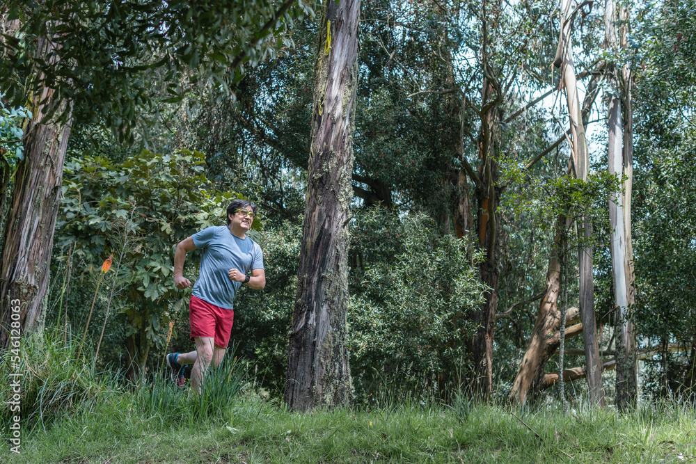 Latino man running in a morning in the middle of a forest