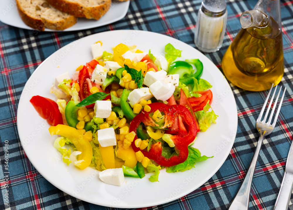 Popular all over the world appetizing vegetable salad made of tomatoes, Feta cheese, lettuce leaves, canned corn and pepper