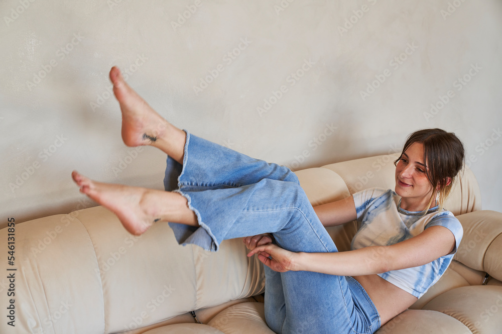 Fototapeta premium woman on sofa balancing with toes pointed 