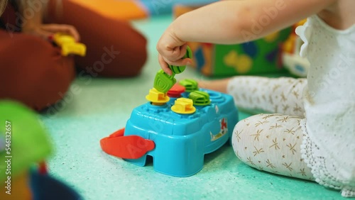 closeup shot of a kid and a teacher playing with toys together, sitting on the floor, games in kindergarten. High quality 4k footage photo