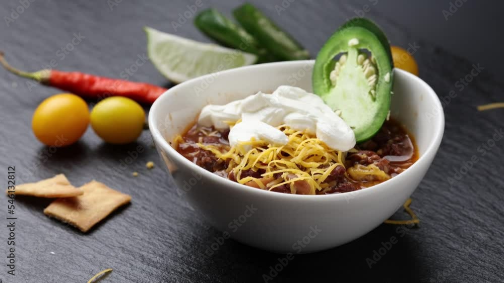 Garnishing a bowl of chili with jalapeño pepper and slice of lime