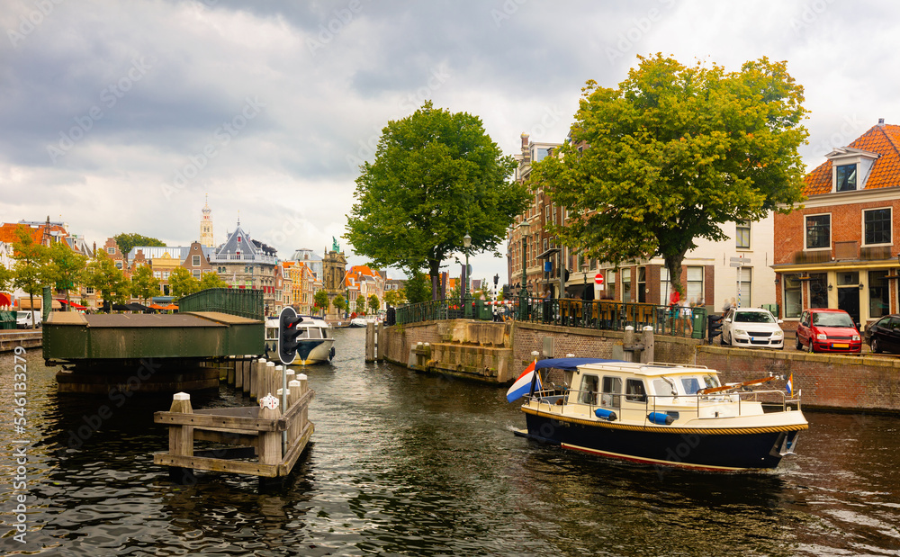 View of Catharijnebrug swing bridge over Spaarne river with passing boats in center of Dutch city of Haarlem on cloudy summer day