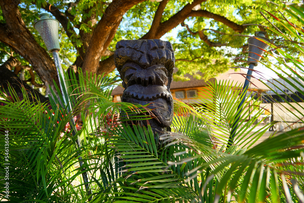 Kapolei, Hawaii / February 23, 2022 : Wooden statue of a tiki god at the Paradise Cove Luau in Ko Olina, a touristic area on the western shore of O'ahu island in Hawaii, United States - obrazy, fototapety, plakaty 