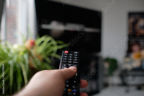 man is holding a TV remote while selecting a program on the flat screen TV in the livingroom