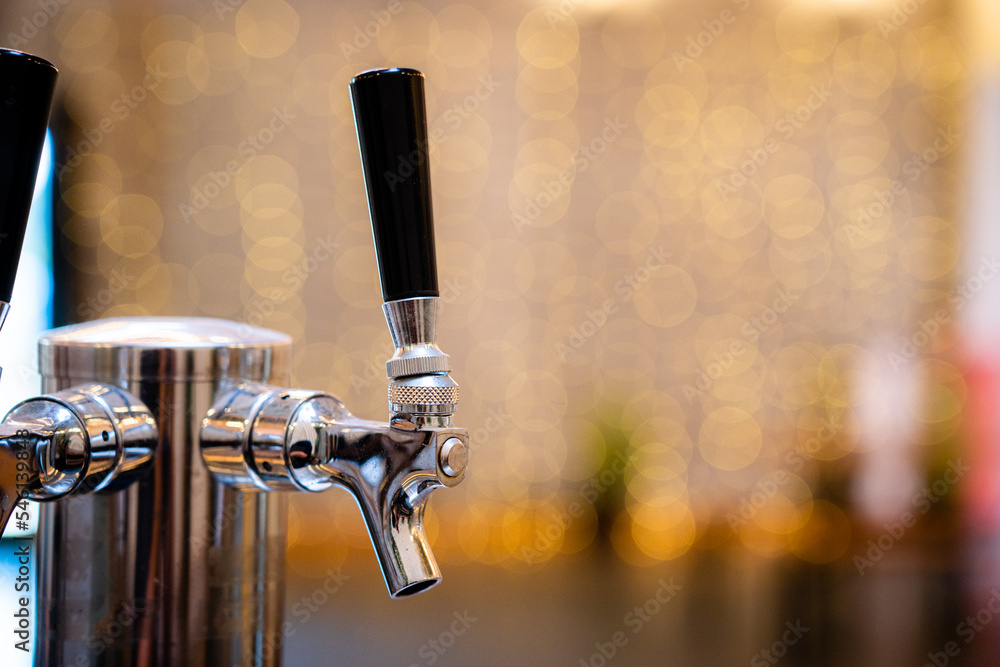Silver Steel Beer Tap at Brewery Pub with No People and Yellow Twinkle Blurred Background
