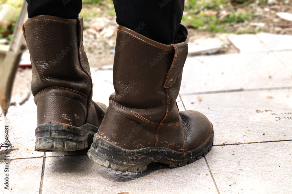 Brown leather safety shoes that are being used by construction workers to protect their feet from work accidents Brown leather safety shoes that are being used by construction workers to protect their feet from work accidents