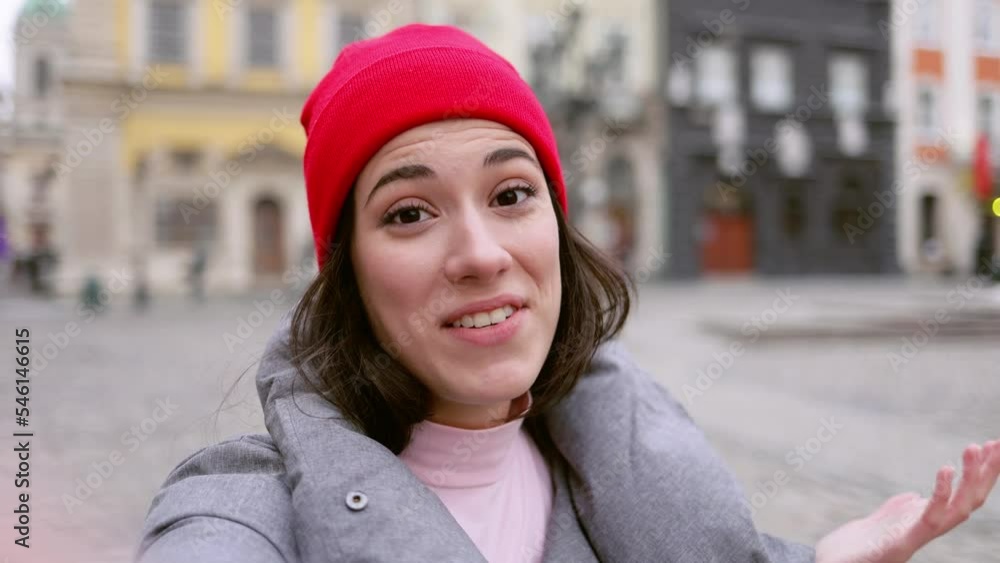 Smiling Blogger influencer speaking to camera phone recording vlog for channel. Young woman speaking to camera phone recording. Girl wearing warm clothes standing in the Center of Town. Smiling Blogger influencer speaking to camera phone recording vlog for channel. Young woman speaking to camera phone recording. Girl wearing warm clothes standing in the Center of Town.
