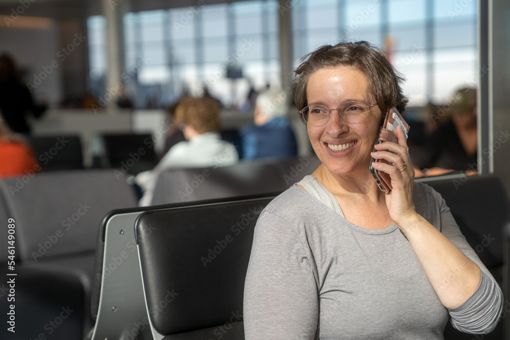 Happy Woman on her phone in airport looking away from the camera Happy Woman on her phone in airport looking away from the camera