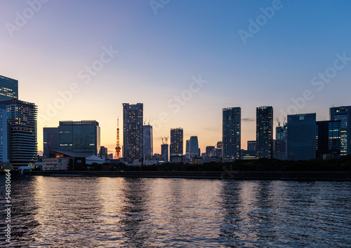 Tokyo tower through tall residential buildings along river at sunset
