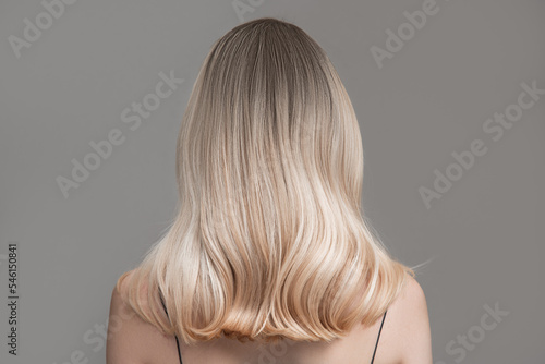 Blonde woman with transitional ombre. back view hair. Grey background