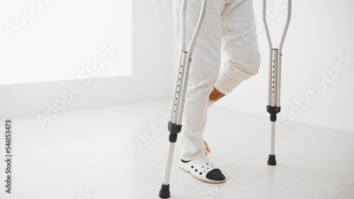 松葉杖をついて歩くミドル男性　リハビリイメージ
