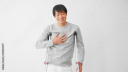 安堵の表情をする松葉杖をついたミドル男性 医療保険イメージ
