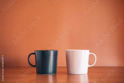 Black and Pink ceramic coffee cup on wood desk with brown background. 