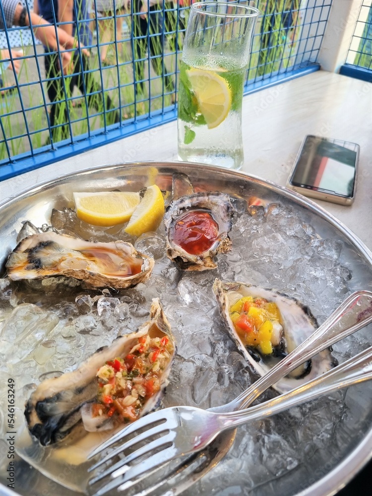 Fresh oysters with ice and lemon on a metal plate Fresh oysters with ice and lemon on a metal plate