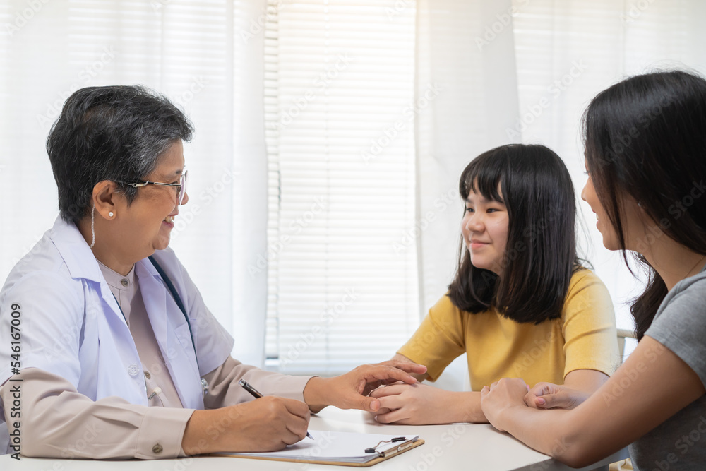 Aged asian physician psychiatrist, general woman doctor holds the patient's hand to encourage the patient girl, child at the appointment at clinic, hospital. Health care, check up medical. Aged asian physician psychiatrist, general woman doctor holds the patient's hand to encourage the patient girl, child at the appointment at clinic, hospital. Health care, check up medical.