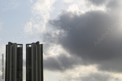 Tall towers of a high rise skyscraper with a background of a cloudy monsoon sky.